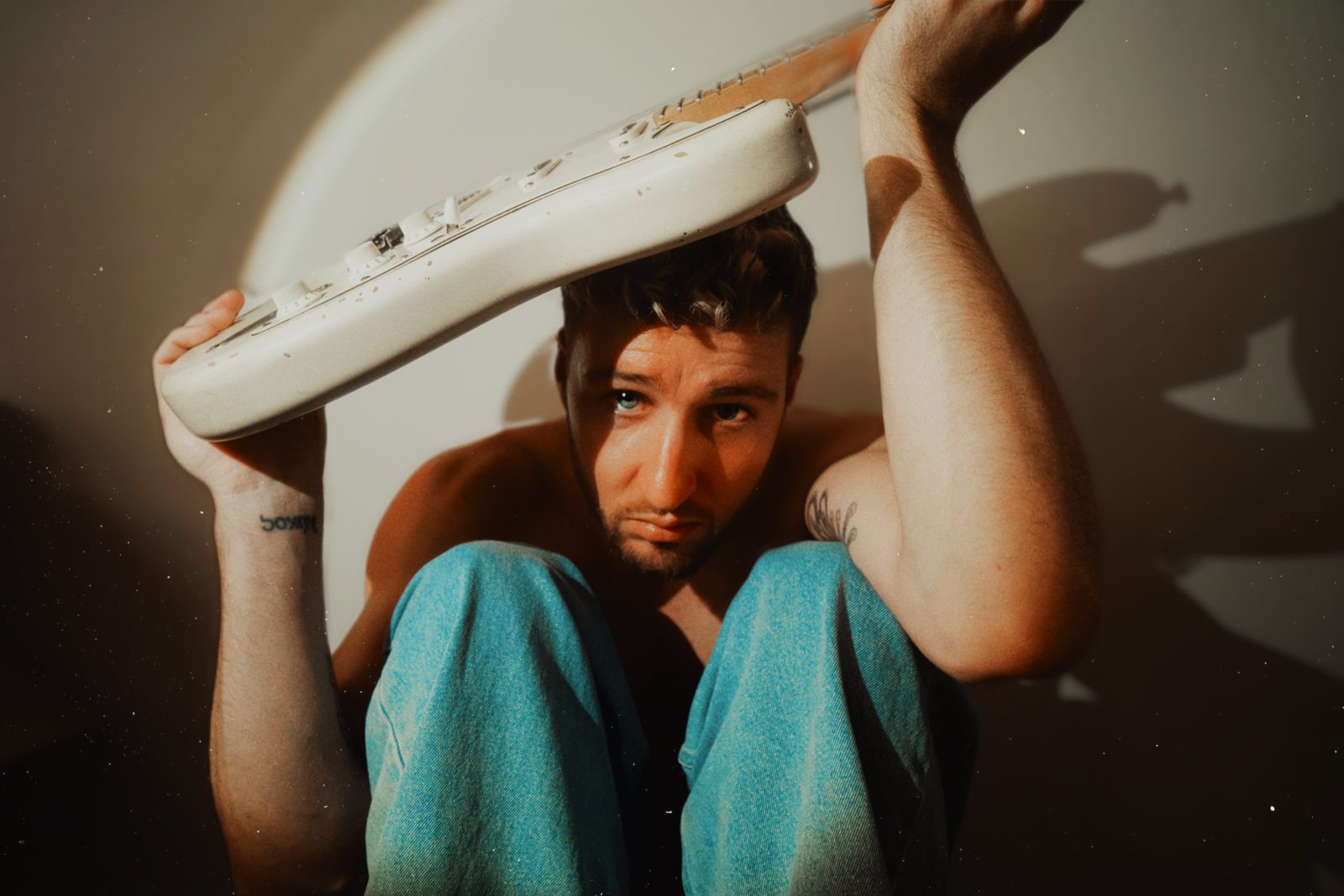 Flozinho holding a white guitar over his head